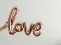 Różowe balony w kształcie napisu "love" unoszą się w powietrzu, tworząc piękną definicję miłości.