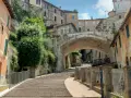 Perugia zwiedzanie: malownicze schody prowadzące pod zabytkowy most, otoczone kamiennymi domami i zielenią.