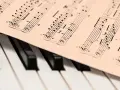 Partytura muzyczna na klawiaturze pianina. Zapis nutowy, który pomaga zrozumieć, co oznacza opus w muzyce, czyli numer dzieła kompozytora.