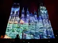 Katedra w Rouen oświetlona projekcjami w kolorach niebieskim i zielonym, z widocznymi żaglówkami.