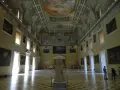 Wnętrze muzeum archeologicznego w Neapolu. Olśniewające sklepienie, obrazy na ścianach i rzeźba w centrum.