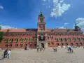 Zwiedzanie Zamku Królewskiego w Warszawie. Tłum turystów na dziedzińcu przed zabytkowym budynkiem.