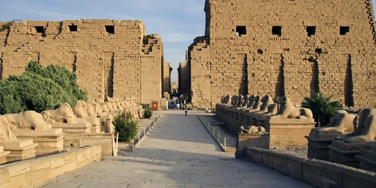 Aleja sfinksów prowadzi do monumentalnych murów świątyni Karnak.