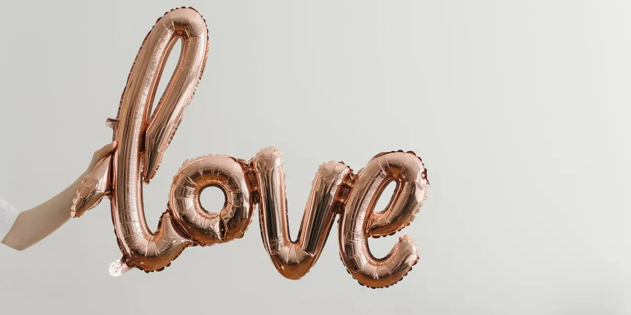 Różowe balony w kształcie napisu "love" unoszą się w powietrzu, tworząc piękną definicję miłości.