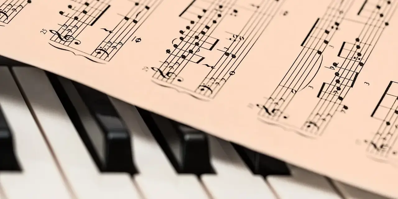 Partytura muzyczna na klawiaturze pianina. Zapis nutowy, który pomaga zrozumieć, co oznacza opus w muzyce, czyli numer dzieła kompozytora.