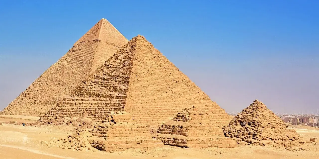 Piramida Cheopsa i inne piramidy na pustyni Giza, majestatyczne budowle starożytnego Egiptu, pod błękitnym niebem.