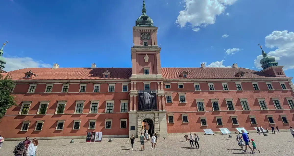 Zwiedzanie Zamku Królewskiego w Warszawie. Tłum turystów na dziedzińcu przed zabytkowym budynkiem.