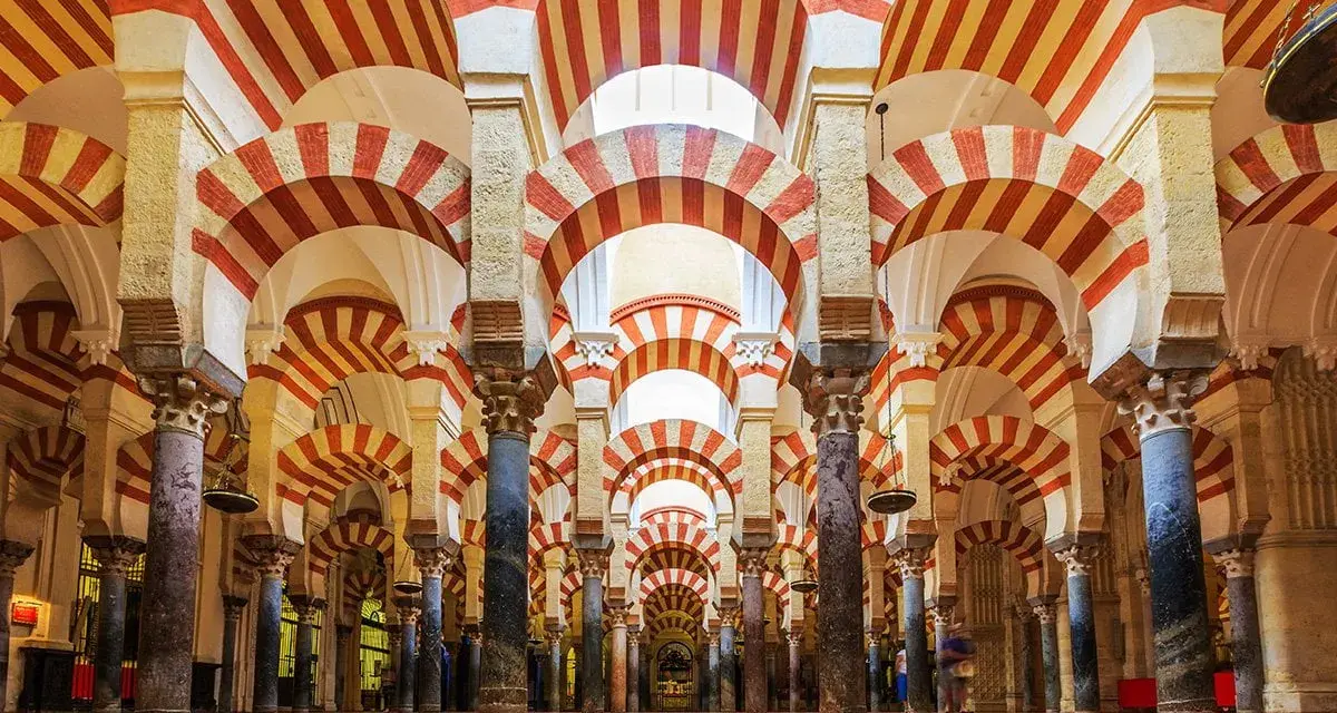 Wnętrze Mezquita w Kordobie z charakterystycznymi łukami w biało-czerwone pasy, tworzącymi hipnotyzujący wzór.