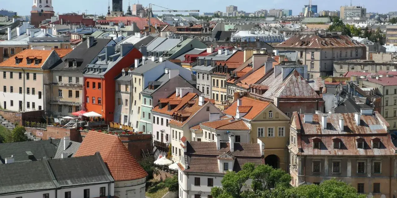 Widok na kolorowe kamienice Starego Miasta w Lublinie, z charakterystyczną wieżą zamkową w tle.