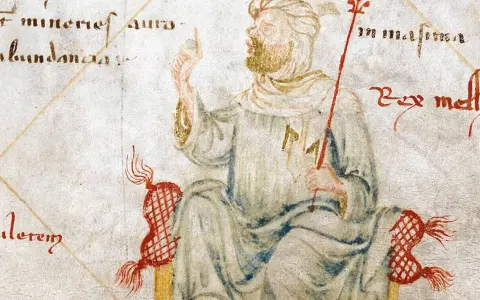 Ilustracja przedstawia Mansę Musę, władcę Mali, symbolizującego jego ogromny majątek. Król siedzi na tronie, trzymając berło.