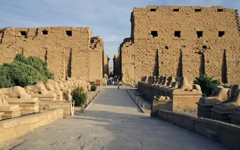 Aleja sfinksów prowadzi do monumentalnych murów świątyni Karnak.