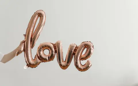 Różowe balony w kształcie napisu "love" unoszą się w powietrzu, tworząc piękną definicję miłości.
