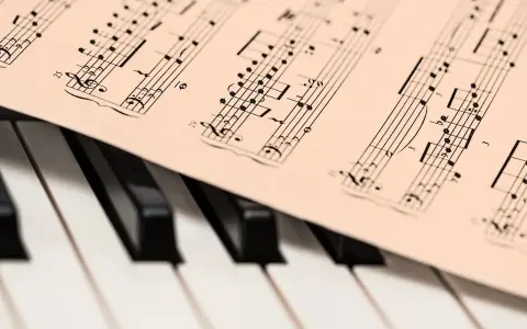 Partytura muzyczna na klawiaturze pianina. Zapis nutowy, który pomaga zrozumieć, co oznacza opus w muzyce, czyli numer dzieła kompozytora.