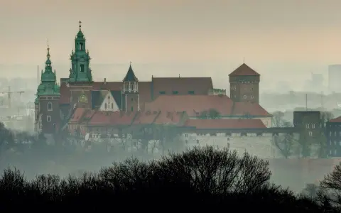 Mglisty poranek nad Wawelem, którego budowę rozpoczęto wieki temu. Zamek królewski wznosi się majestatycznie na wzgórzu.