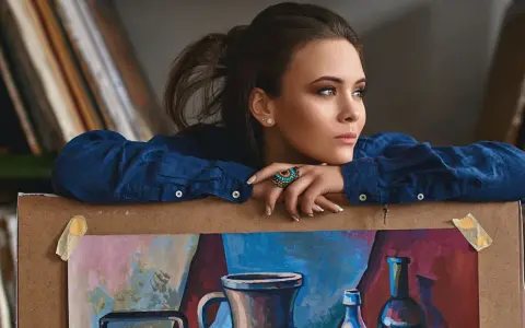 Młoda artystka, jak malarze XX wieku, spogląda zamyślona na swoje dzieło.