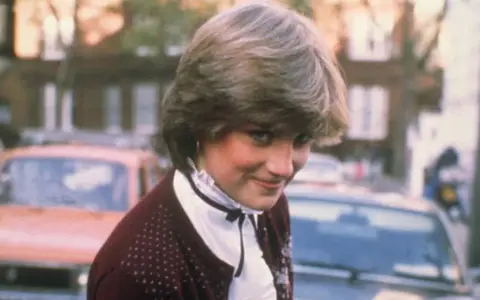 Młoda Diana Spencer, zanim została księżną, w bordowym sweterku i białej bluzce. Jej arystokratyczne pochodzenie widać w subtelnych gestach.