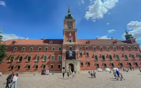 Zwiedzanie Zamku Królewskiego w Warszawie. Tłum turystów na dziedzińcu przed zabytkowym budynkiem.