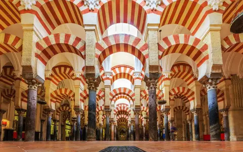 Wnętrze Mezquita w Kordobie z charakterystycznymi łukami w biało-czerwone pasy, tworzącymi hipnotyzujący wzór.