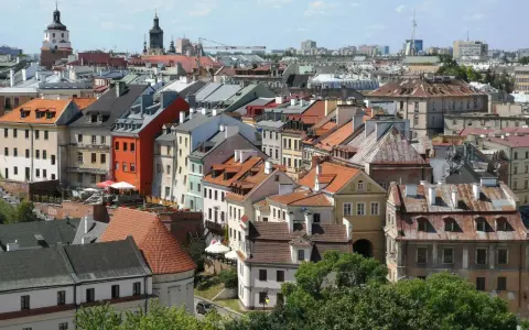 Widok na kolorowe kamienice Starego Miasta w Lublinie, z charakterystyczną wieżą zamkową w tle.