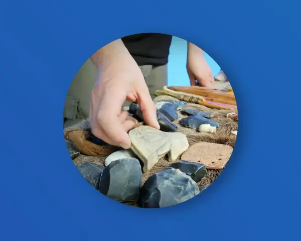 Ręka wybiera kamienną figurkę bizona wśród narzędzi i artefaktów. Zakazana archeologia najnowsze odkrycia.