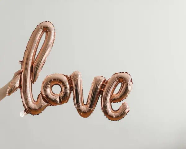 Różowe balony w kształcie napisu "love" unoszą się w powietrzu, tworząc piękną definicję miłości.