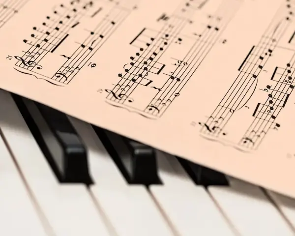 Partytura muzyczna na klawiaturze pianina. Zapis nutowy, który pomaga zrozumieć, co oznacza opus w muzyce, czyli numer dzieła kompozytora.
