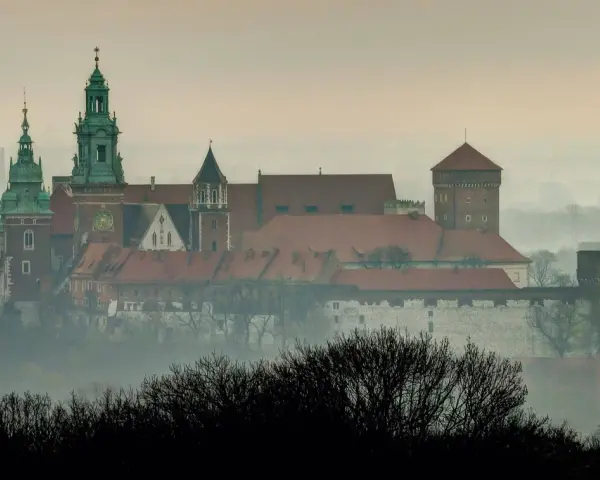 Mglisty poranek nad Wawelem, którego budowę rozpoczęto wieki temu. Zamek królewski wznosi się majestatycznie na wzgórzu.