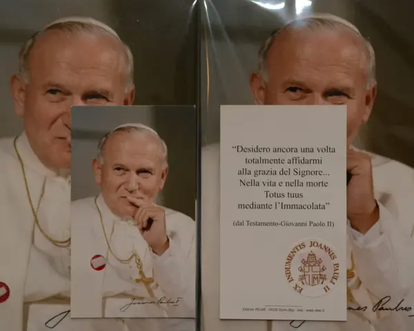 Relikty Jana Pawła II. Na zdjęciu papież w białej szacie, z krzyżem na szyi. Obok cytat z jego testamentu.