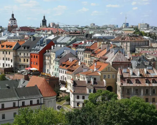 Widok na kolorowe kamienice Starego Miasta w Lublinie, z charakterystyczną wieżą zamkową w tle.