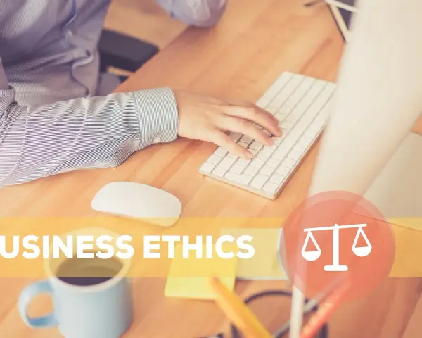 Osoba pracuje przy biurku, klawiatura i myszka. Napis "BUSINESS ETHICS" i symbol wagi. To jest etyka co to.