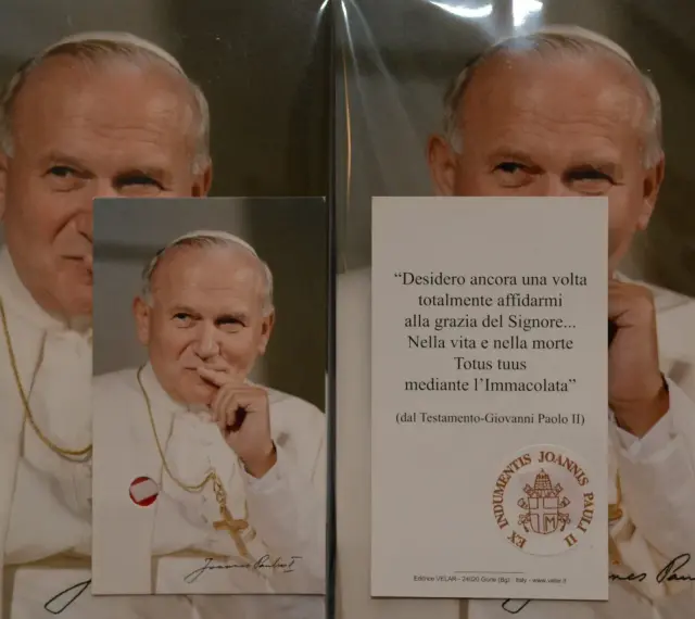 Relikty Jana Pawła II. Na zdjęciu papież w białej szacie, z krzyżem na szyi. Obok cytat z jego testamentu.