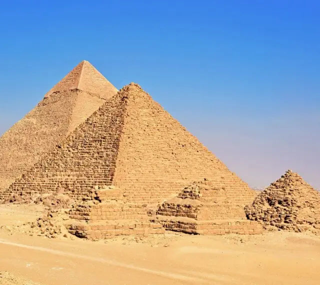 Piramida Cheopsa i inne piramidy na pustyni Giza, majestatyczne budowle starożytnego Egiptu, pod błękitnym niebem.