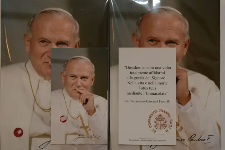 Relikty Jana Pawła II. Na zdjęciu papież w białej szacie, z krzyżem na szyi. Obok cytat z jego testamentu.