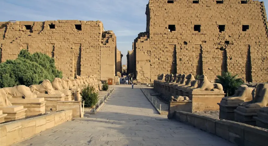 Aleja sfinksów prowadzi do monumentalnych murów świątyni Karnak.