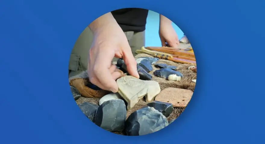 Ręka wybiera kamienną figurkę bizona wśród narzędzi i artefaktów. Zakazana archeologia najnowsze odkrycia.