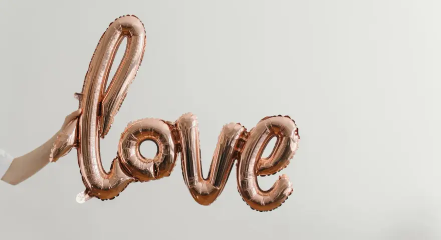 Różowe balony w kształcie napisu "love" unoszą się w powietrzu, tworząc piękną definicję miłości.