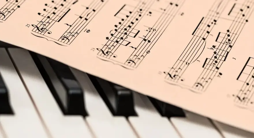 Partytura muzyczna na klawiaturze pianina. Zapis nutowy, który pomaga zrozumieć, co oznacza opus w muzyce, czyli numer dzieła kompozytora.