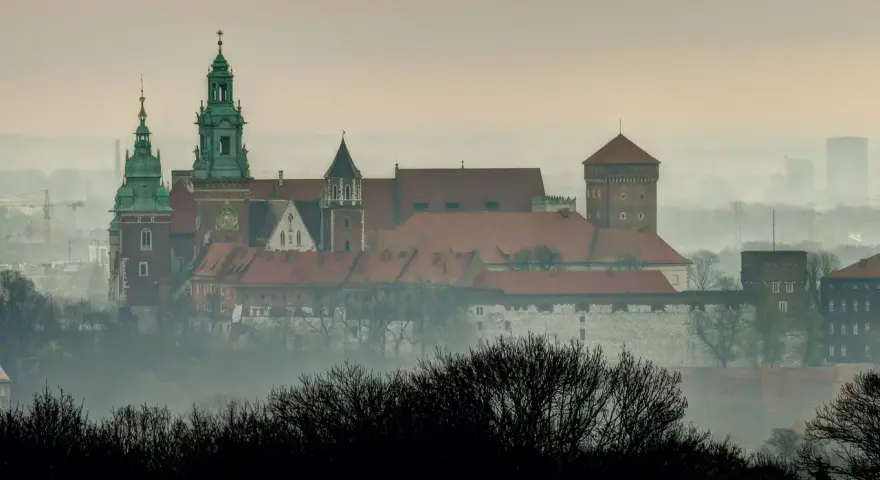 Mglisty poranek nad Wawelem, którego budowę rozpoczęto wieki temu. Zamek królewski wznosi się majestatycznie na wzgórzu.
