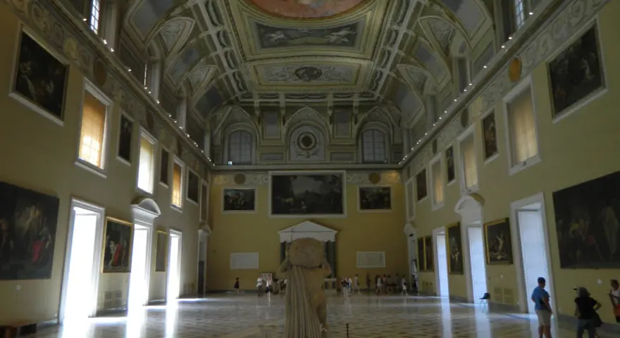 Wnętrze muzeum archeologicznego w Neapolu. Olśniewające sklepienie, obrazy na ścianach i rzeźba w centrum.