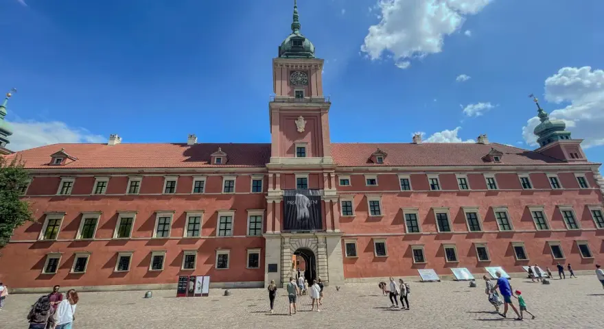 Zwiedzanie Zamku Królewskiego w Warszawie. Tłum turystów na dziedzińcu przed zabytkowym budynkiem.