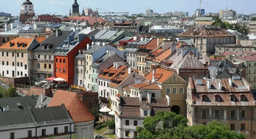 Widok na kolorowe kamienice Starego Miasta w Lublinie, z charakterystyczną wieżą zamkową w tle.