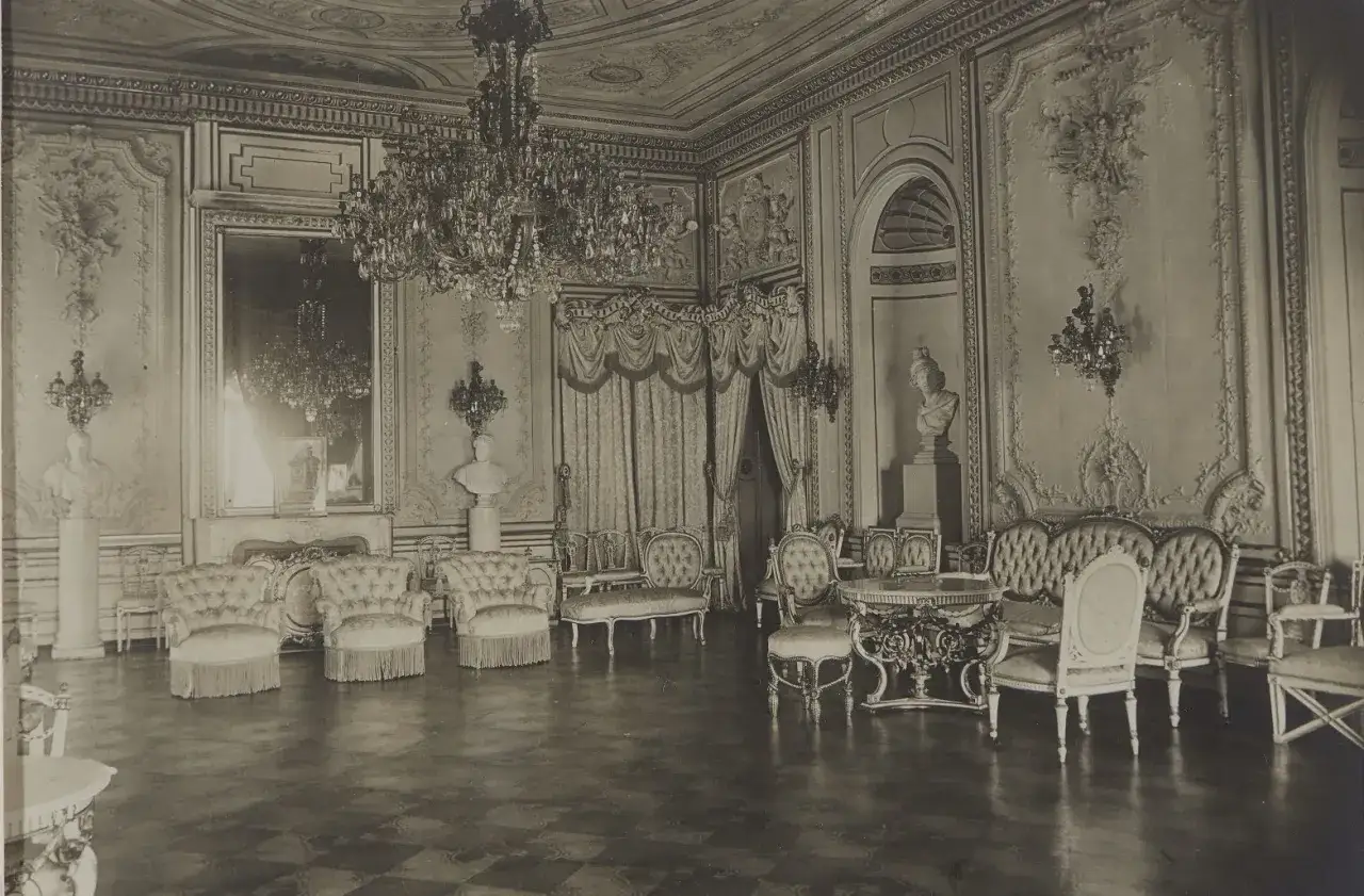 Eleganckie wnętrze podczas zwiedzania zamku kr&oacute;lewskiego. Kryształowy żyrandol, bogato zdobione ściany i stylowe meble tworzą atmosferę luksusu.