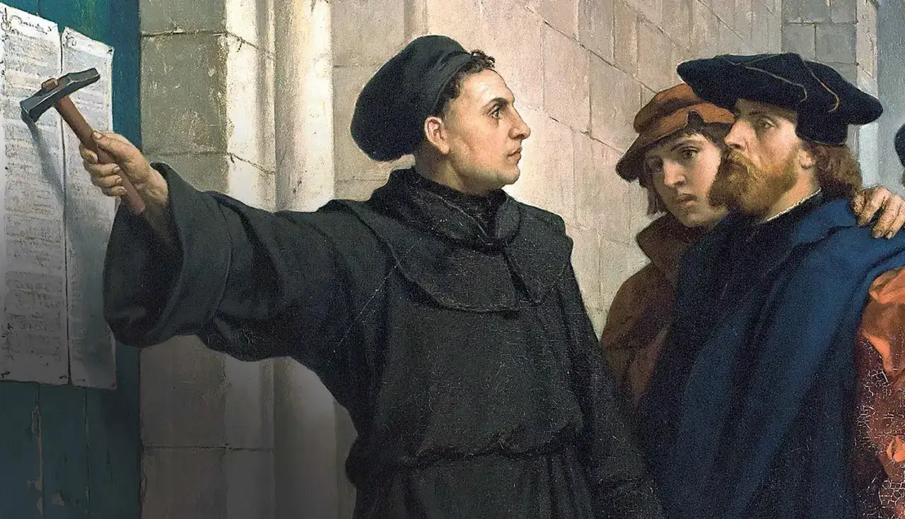 Marcin Luter przybija młotkiem swoje 95 tez do drzwi kościoła, rozpoczynając reformację.