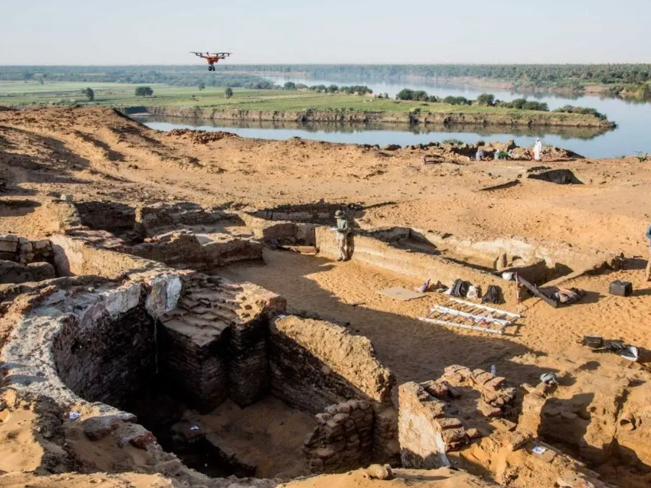 Archeolodzy badają starą Dongolę, odkrywając ruiny. W powietrzu unosi się dron, dokumentując prace.